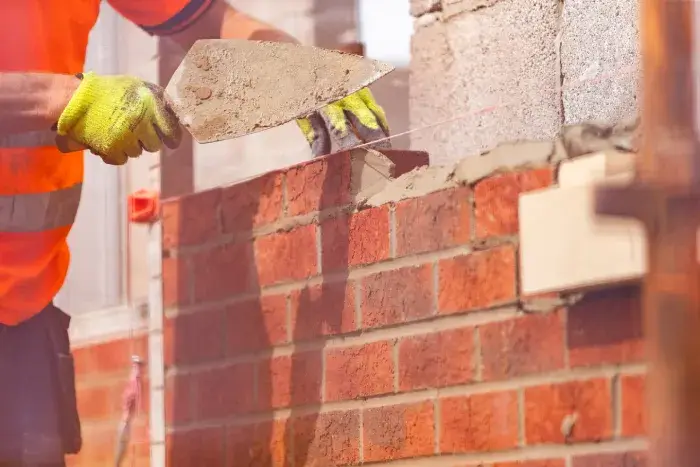 Hands putting mortar on bricks